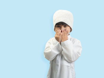 Portrait of boy praying against blue background