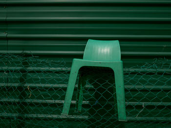 Close-up of plastic chair on chainlink fence