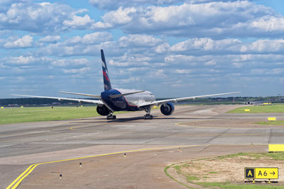 Airplane flying over runway against sky