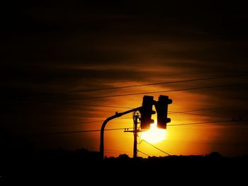 Low angle view of silhouette street light against orange sky