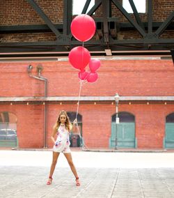 Full length portrait of woman with pink balloons