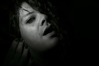 Close-up portrait of woman against black background