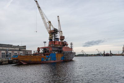 Cranes at commercial dock against sky