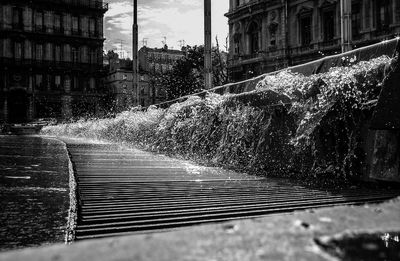 Water splashing on fountain in city against sky