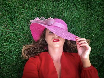 Portrait of young wearing wearing summer hat while lying down on the green grass