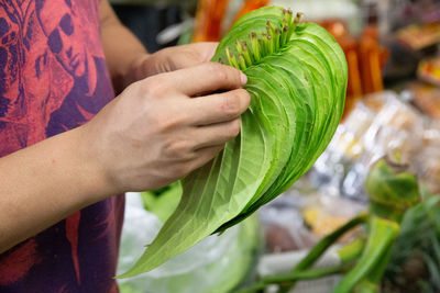 Stitching leaves together in bangkok flower market.