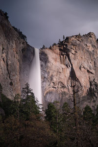 Scenic view of waterfall against cloudy sky