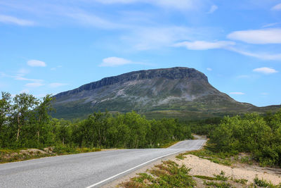 Empty road by mountains against sky