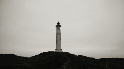 Low angle view of lighthouse on hill against sky at dusk