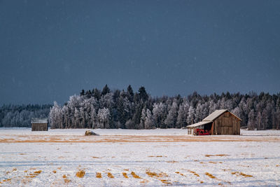 House on field by trees against sky during winter