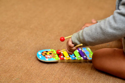 Midsection of child playing xylophone at home