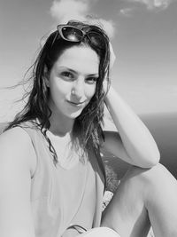 Portrait of young woman in sunglasses sitting against sea