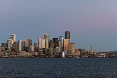 Sea by cityscape against clear sky