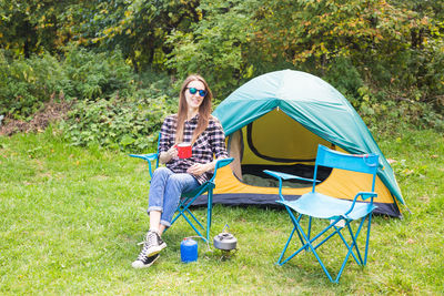 Woman sitting in tent on field