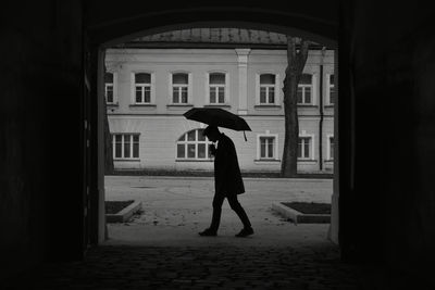 Silhouette of a man walking under an umbrella