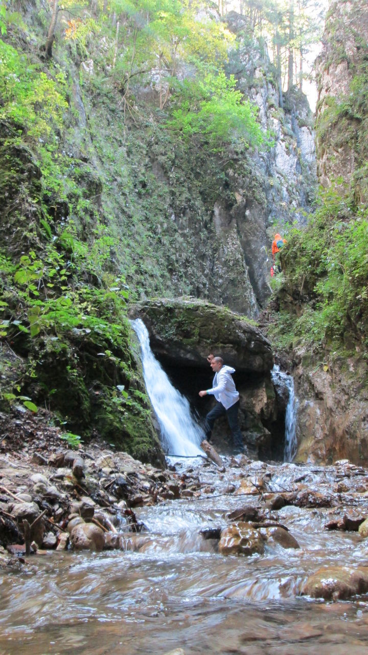 WOMAN IN RIVER FLOWING THROUGH ROCKS