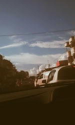 Cars on road in city against sky