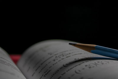 Close-up of pen on book against black background