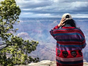 Rear view of woman standing on mountain against sky