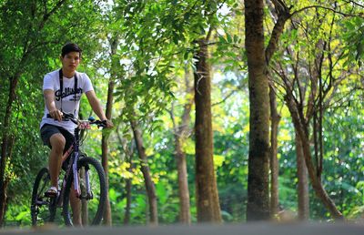 Portrait of young man riding bicycle in forest