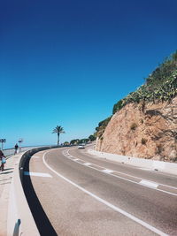 Empty road against clear blue sky