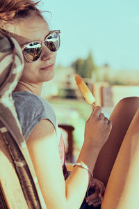 Midsection of woman holding cigarette in sunglasses