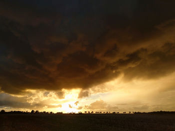 Scenic view of silhouette field against sky during sunset