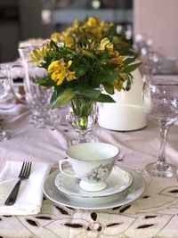 High angle view of flowers in vase by crockeries on dining table