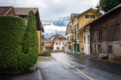 Road amidst houses against sky