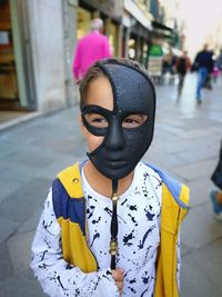 Portrait of boy wearing mask while standing on street