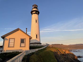 Lighthouse by sea against sky