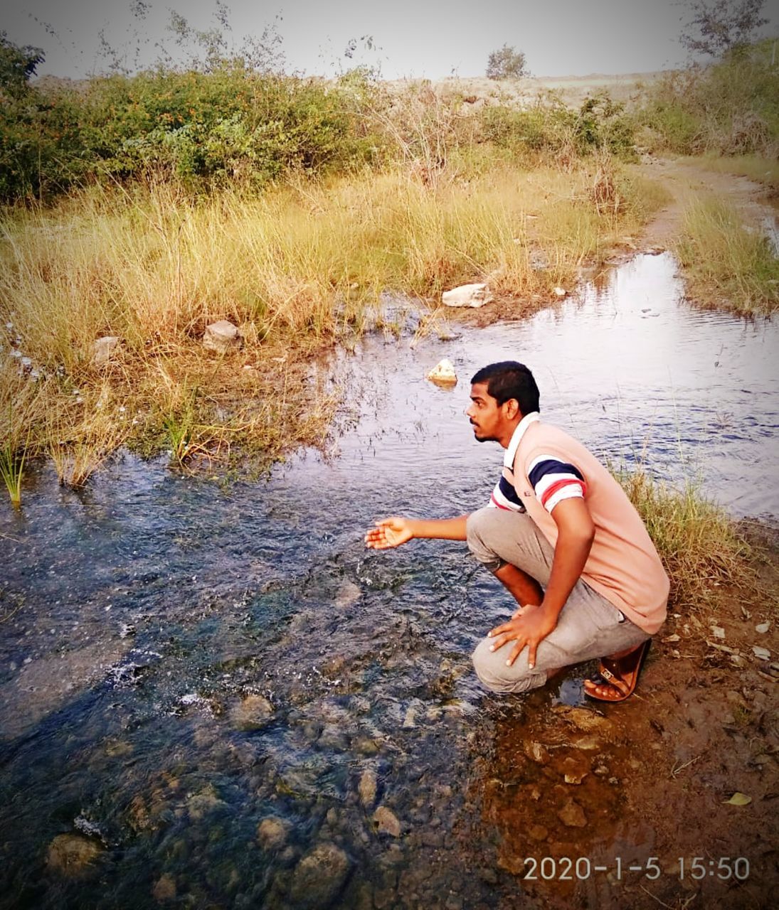 SIDE VIEW OF YOUNG MAN SITTING ON LAKE