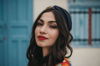 Portrait of young woman standing against door