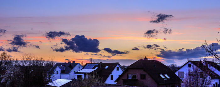 Houses against cloudy sky at sunset