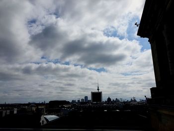 Buildings in city against cloudy sky