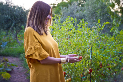 Woman standing by plants on field
