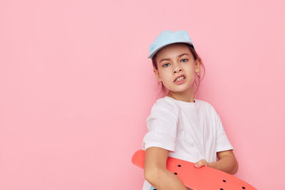 Portrait of cute girl standing against pink background