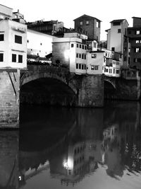 Arch bridge over river against buildings in city