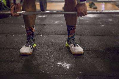 Low section of man lifting dumbbell in gym