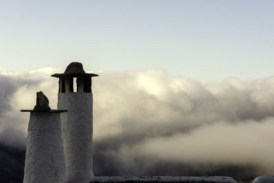 Low angle view of bird perching on tower against sky