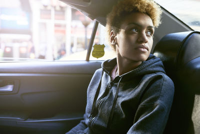 Thoughtful young woman sitting in taxi