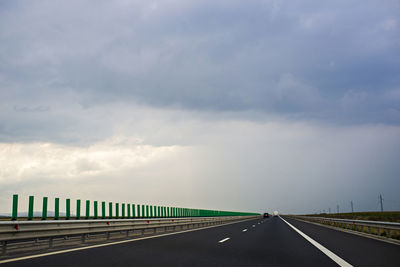 Road leading towards bridge against sky