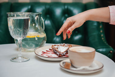 Midsection of woman drinking glass on table at restaurant