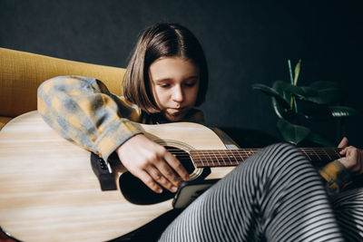 Teenage girl learning to play guitar