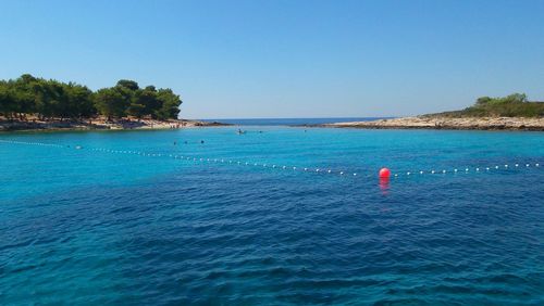 Scenic view of bouy in sea against clear sky