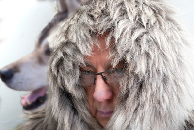 Close-up of serious man wearing fur against dog 