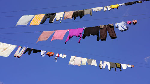 Low angle view of clothes drying against clear blue sky