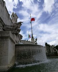 Fountain against cloudy sky