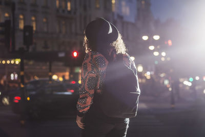 Woman standing on city street at night