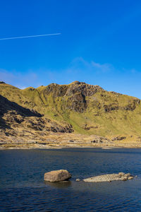 Scenic view of sea and mountains against blue sky